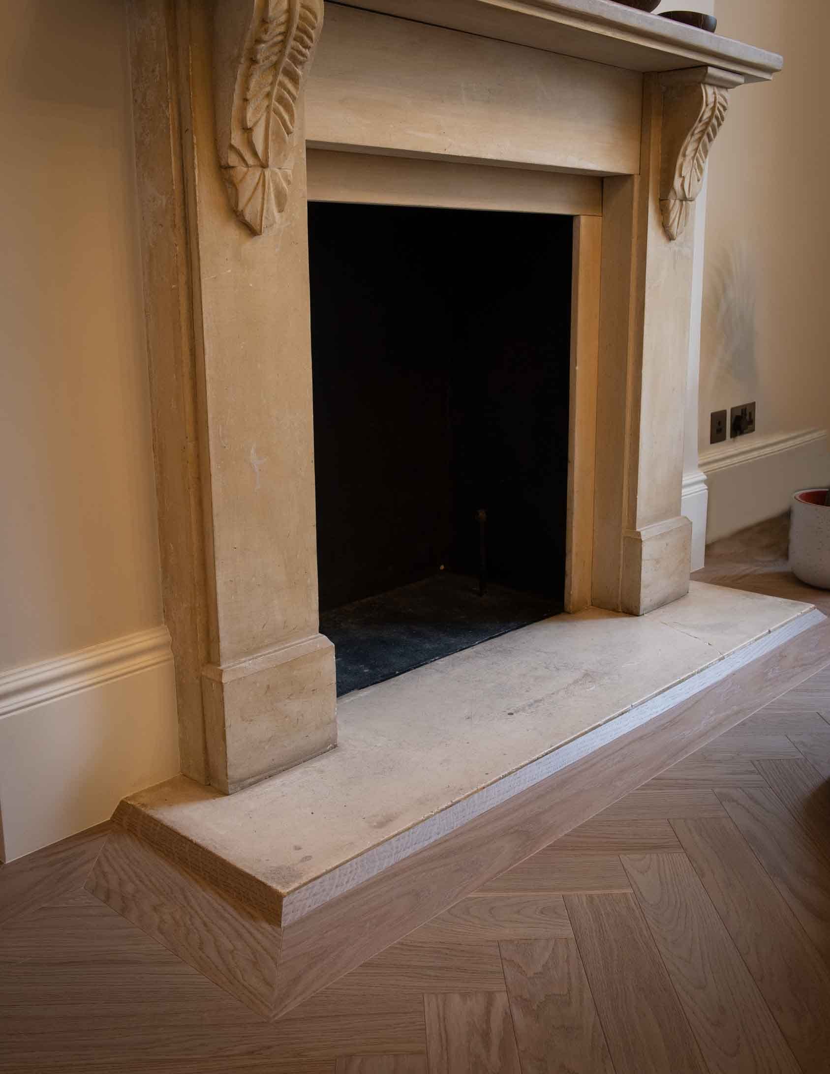 grey brown herringbone wood flooring bordered around fireplace hearth