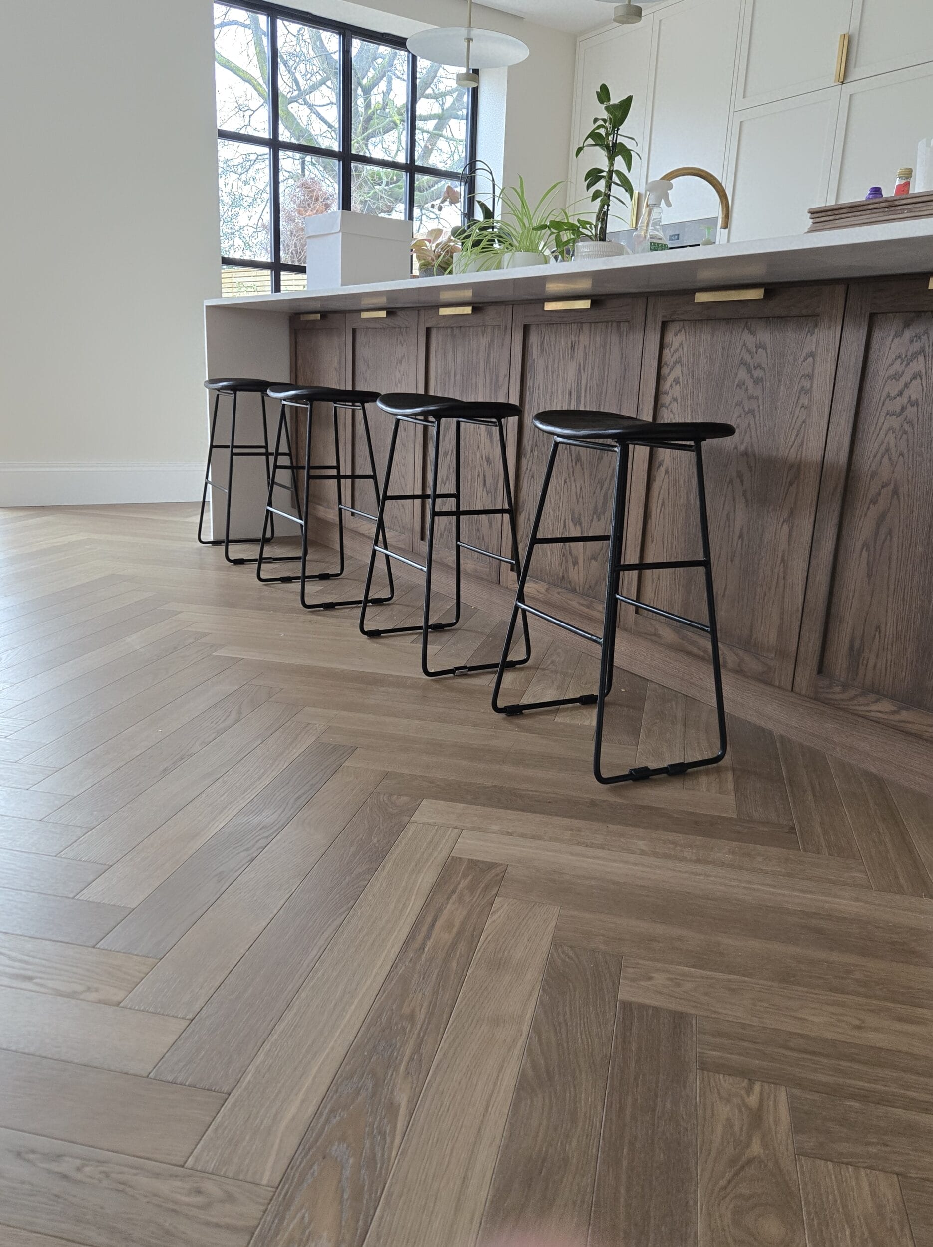 Warm light brown herringbone wood floor in kitchen